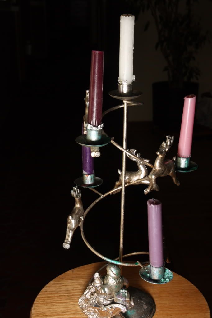 Monstrous silver Santa and Reindeer Candlebra with clashing candles in various shades of purple.